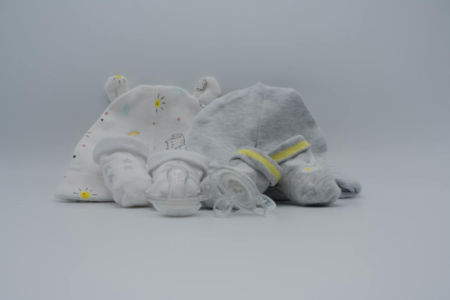 Czapeczki, skarpetki i smoczek niemowlęcy w pastelowych kolorach