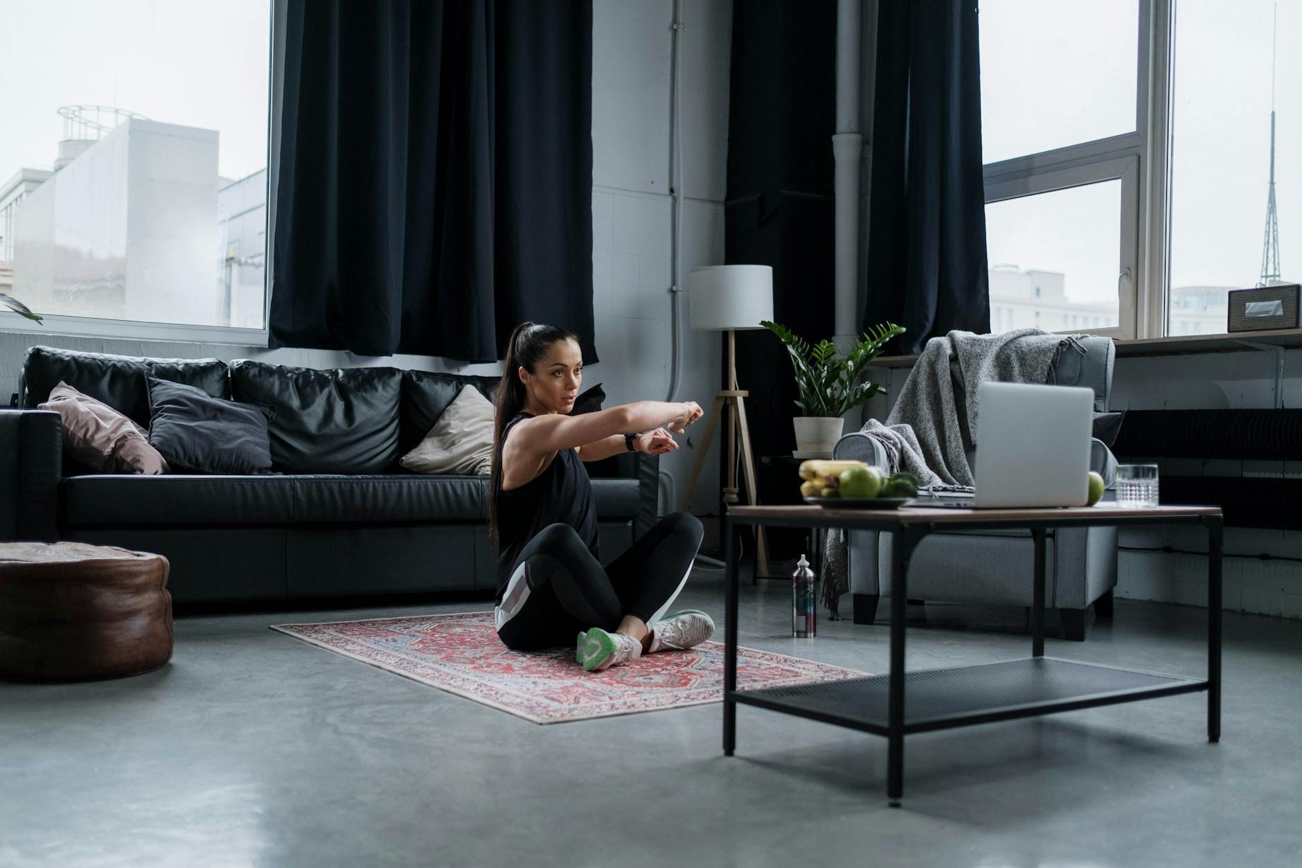 Kobieta w dresie rozciąga się w salonie podczas domowego treningu