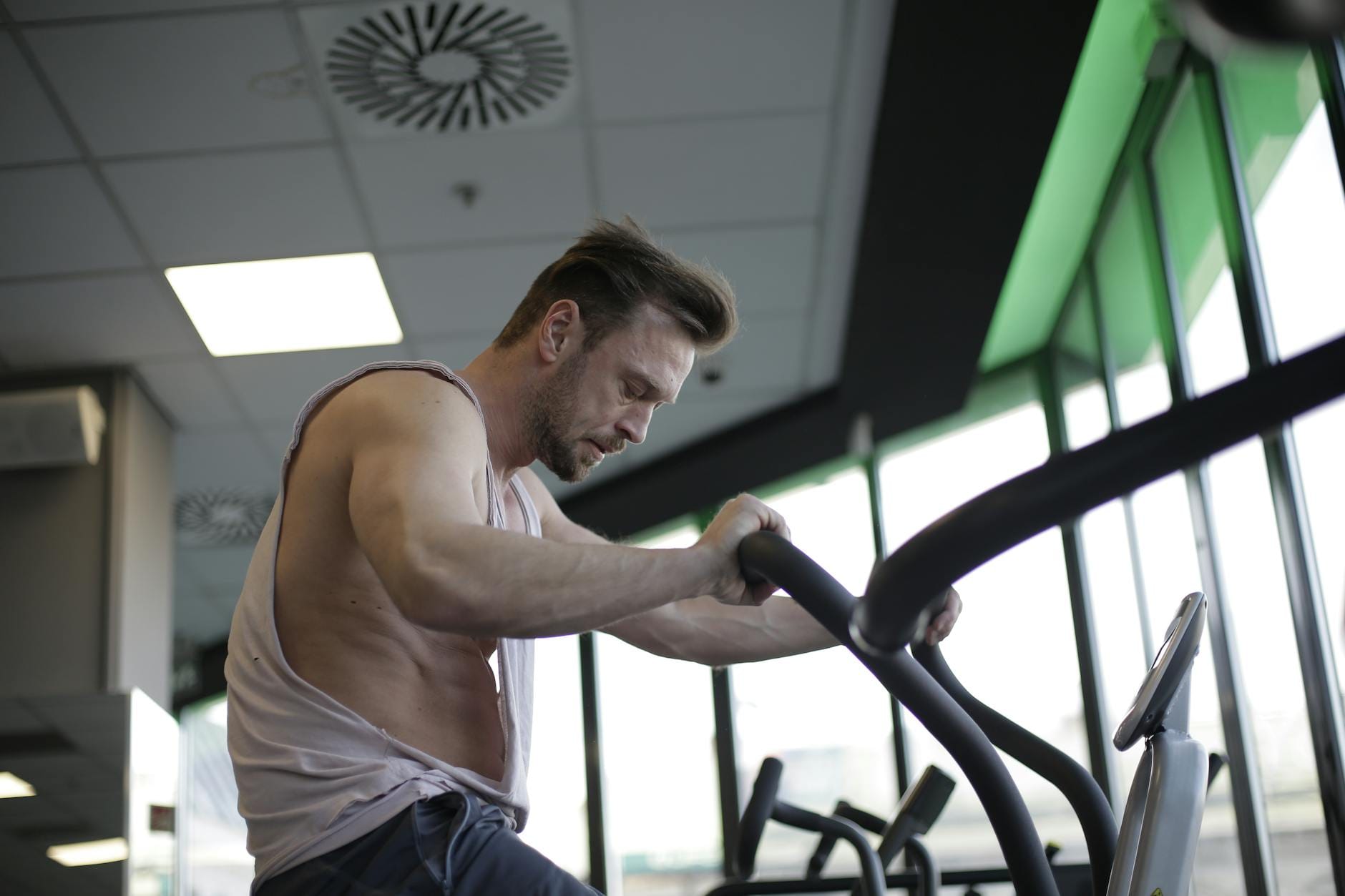 Muskularny mężczyzna na rowerku stacjonarnym w nowoczesnej siłowni