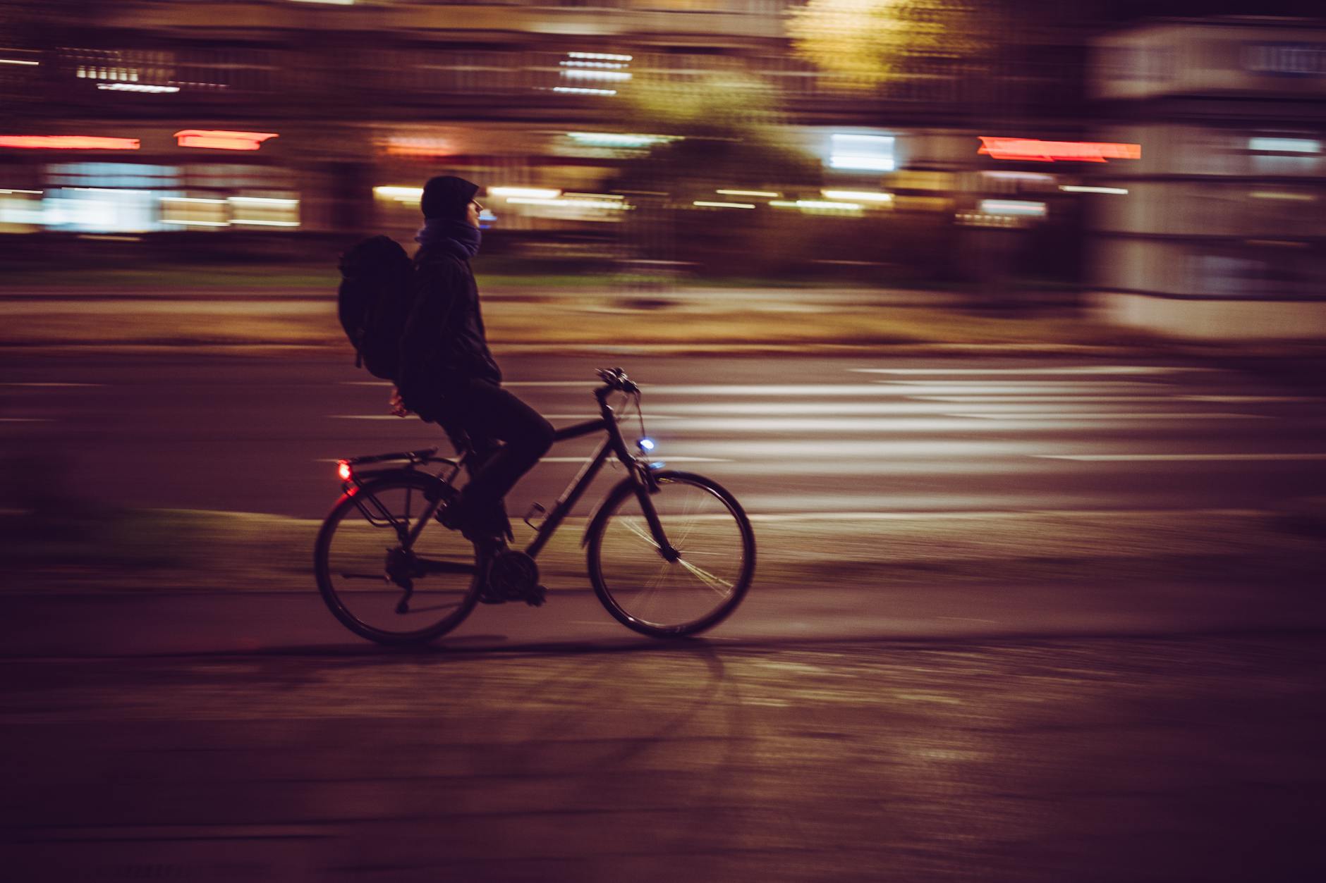 Rozmazany rowerzysta nocą na oświetlonej miejskiej ulicy