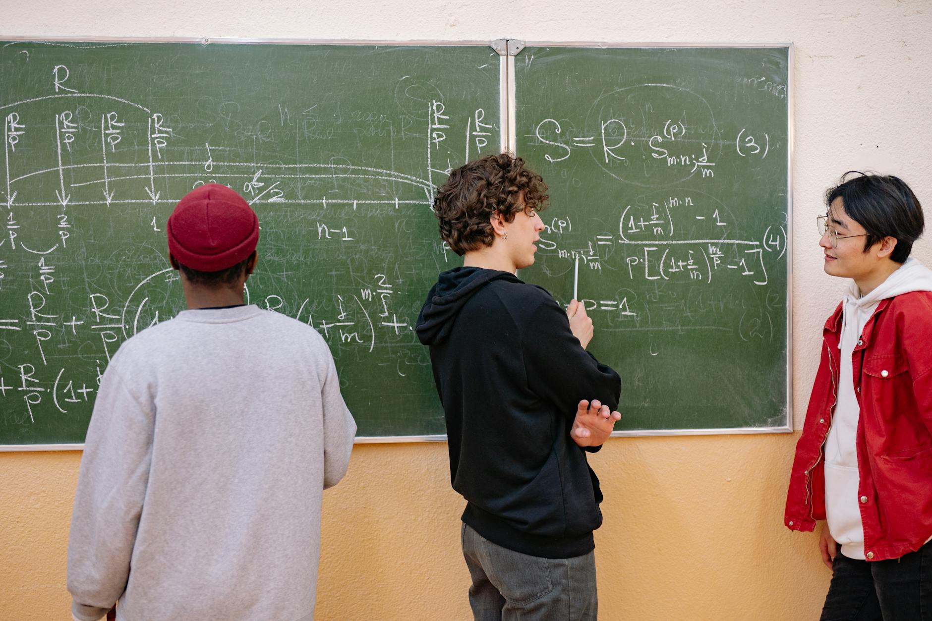Uczniowie omawiają zadania z matematyki przy szkolnej tablicy