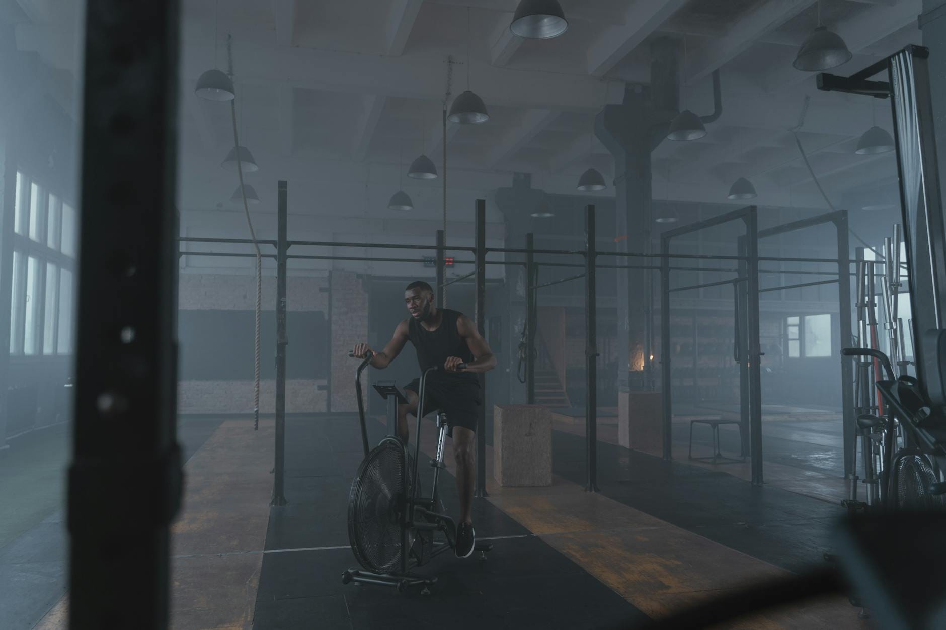 Zawodnik trenujący na rowerku stacjonarnym w industrialnej siłowni