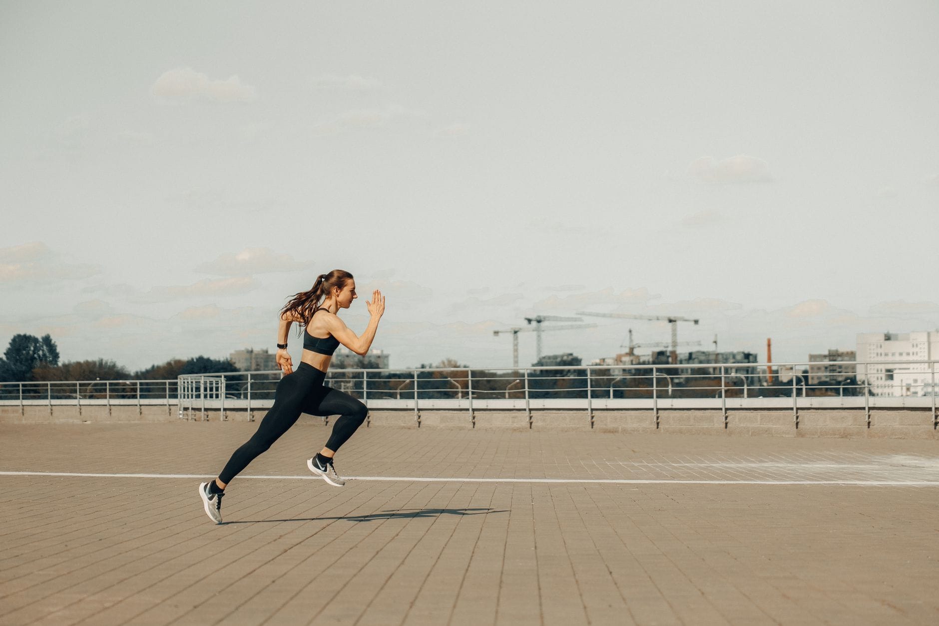 Kobieta w stroju sportowym biegnie sprintem po dachu w słoneczny dzień