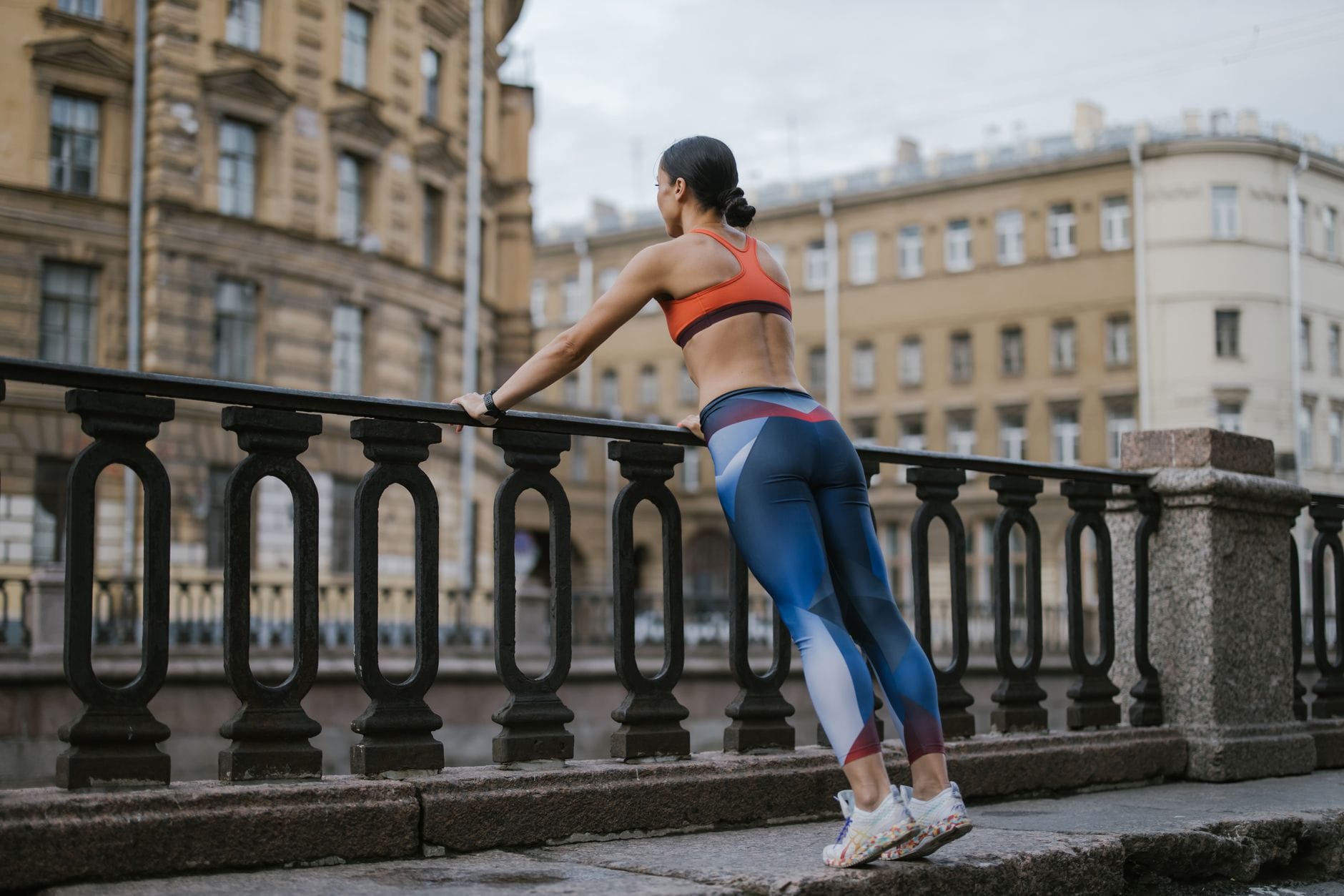 Cardio na świeżym powietrzu: pomysły na trening bez nudy Sportsmenka w stroju treningowym oparta o barierkę w miejskim otoczeniu