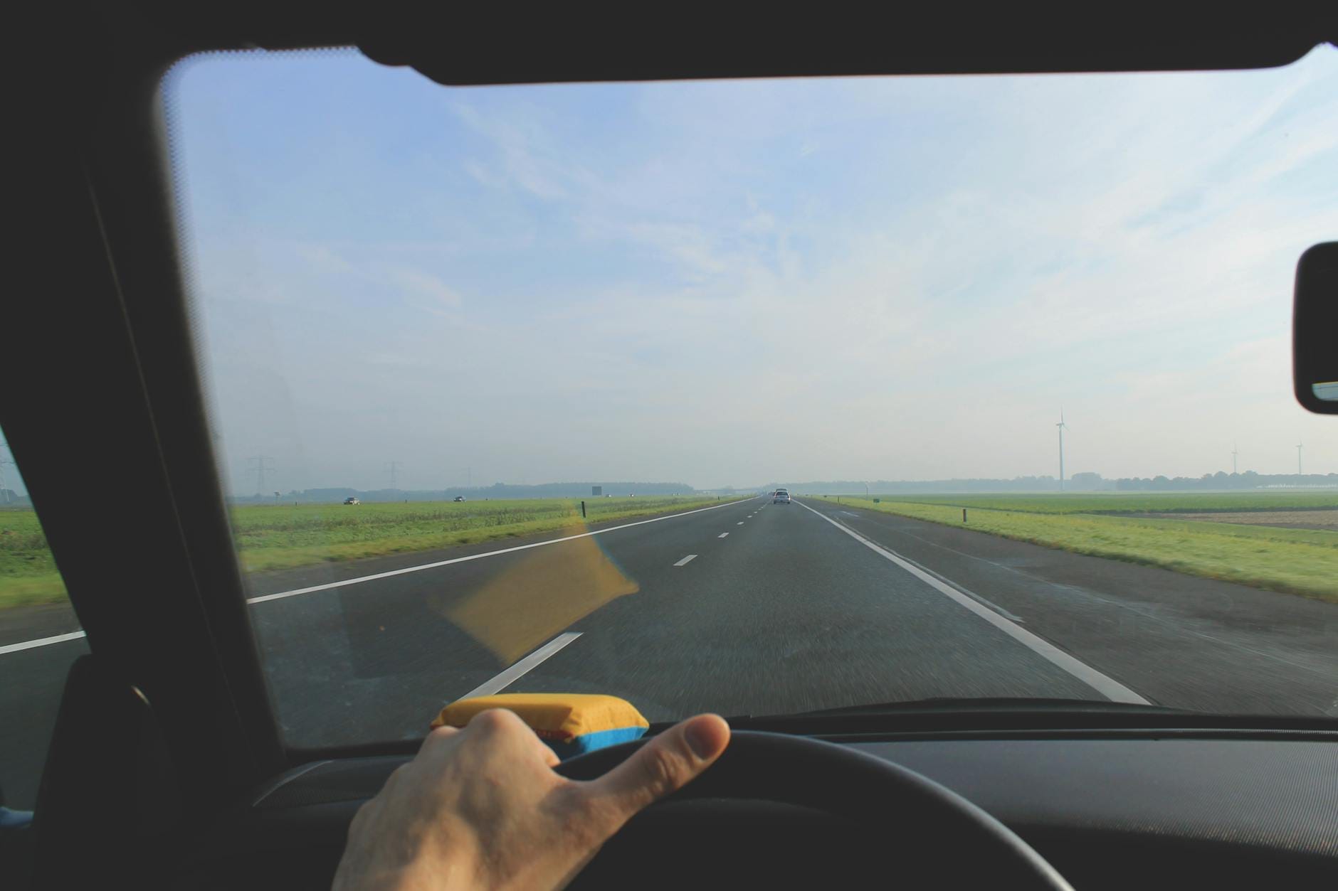 Jak bezpiecznie jeździć po autostradzie: praktyczny poradnik dla początkujących kierowców Widok przez przednią szybę auta na pustą autostradę i zielone pola
