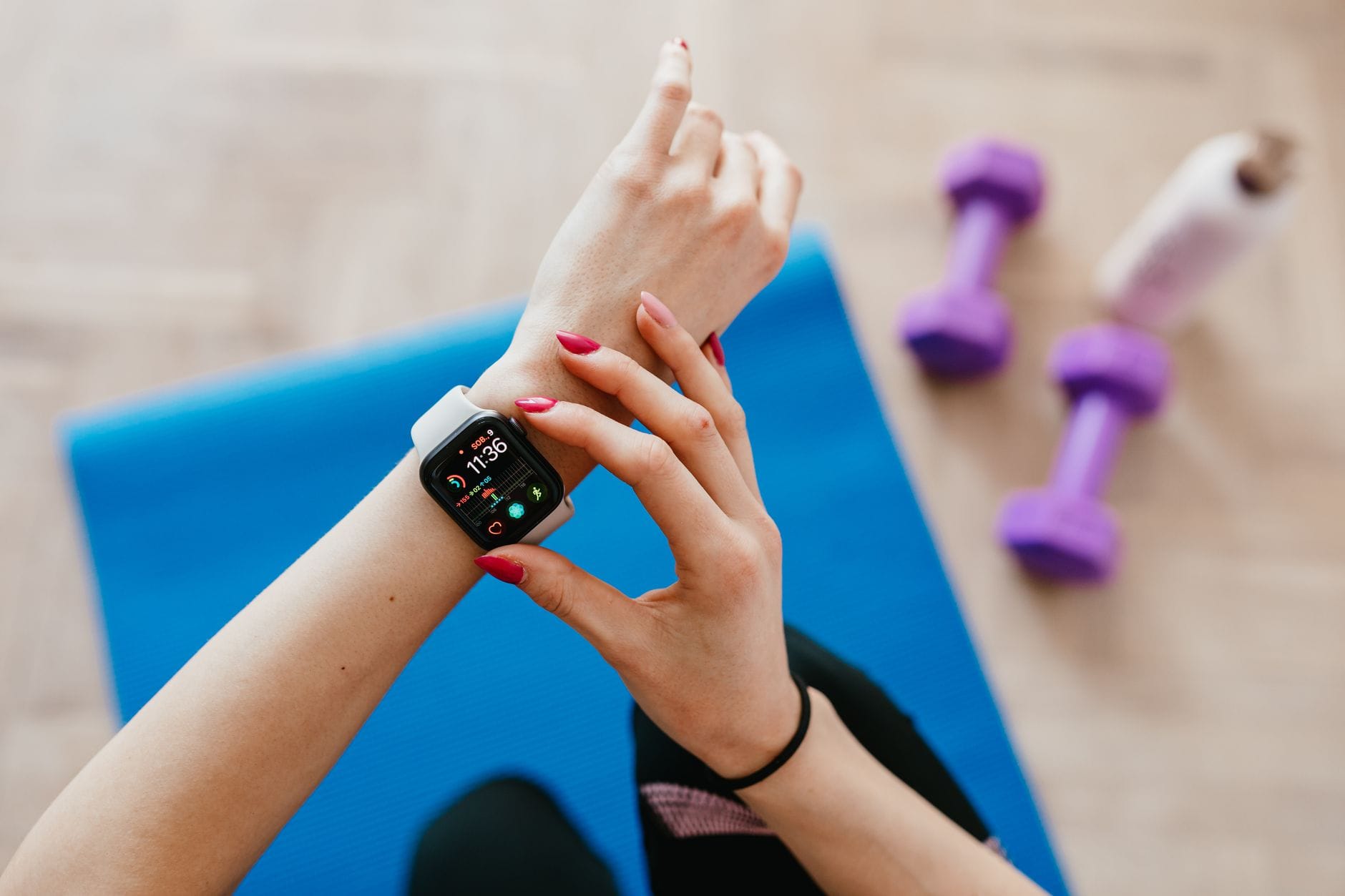 Kobieta w stroju sportowym na macie sprawdza dane na smartwatchu