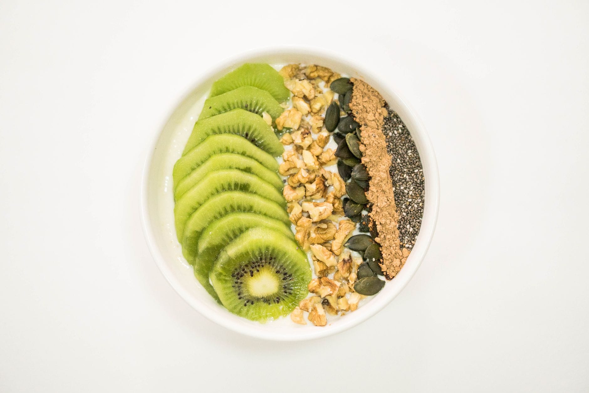 Miseczka smoothie z kiwi, orzechami, nasionami i jogurtem po treningu